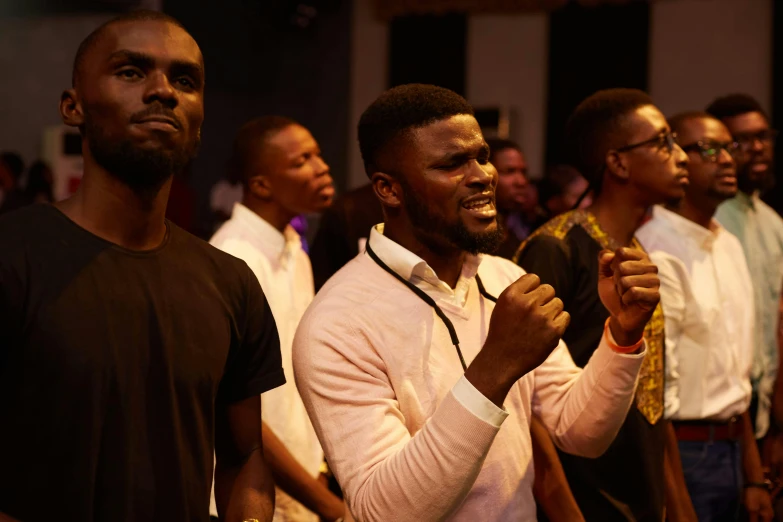 a group of men standing next to each other, by Ingrida Kadaka, pexels, happening, many people worshipping, audience in the background, adebanji alade, listening to godly music
