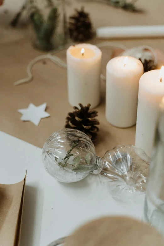 a group of candles sitting on top of a table, by Ruth Simpson, trending on pexels, light and space, fossil ornaments, white ribbon, paper decoration, holiday