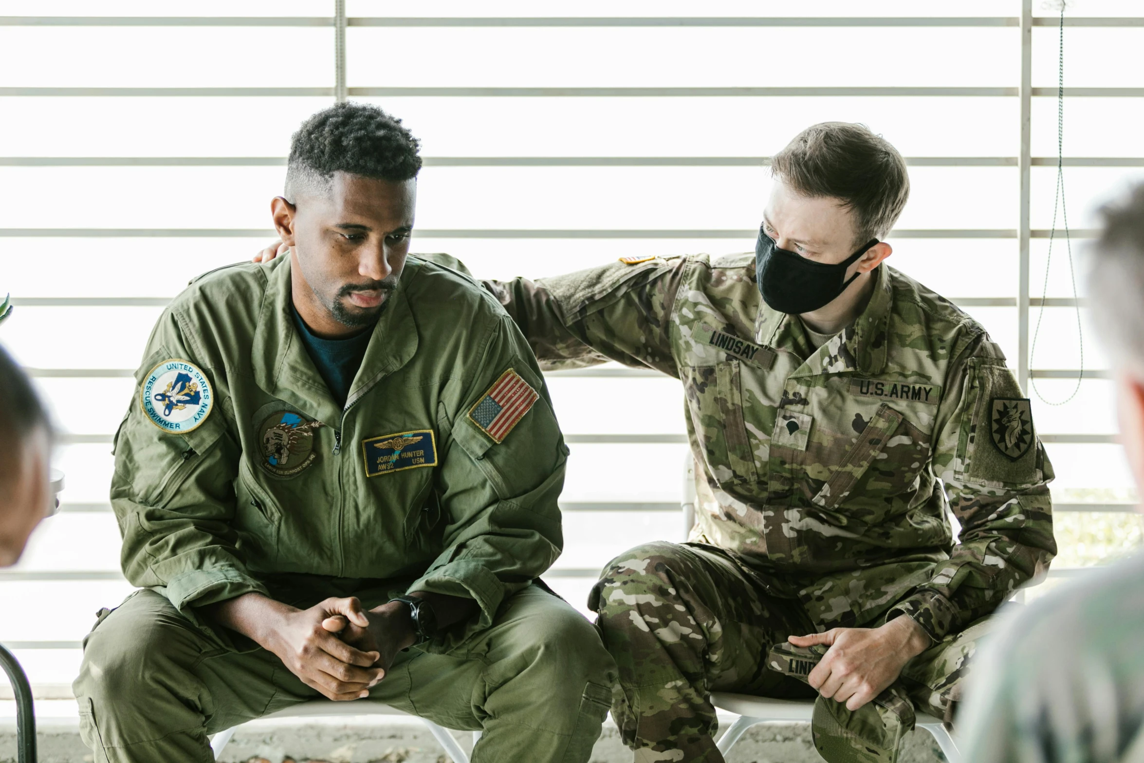 a couple of men sitting next to each other, a colorized photo, pexels, air force jumpsuit, praying, healthcare, wearing a patch over one eye