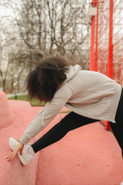 a woman standing on top of a skateboard ramp, pexels contest winner, happening, stretching her legs on the grass, red sweater and gray pants, african american young woman, wearing a pastel pink hoodie