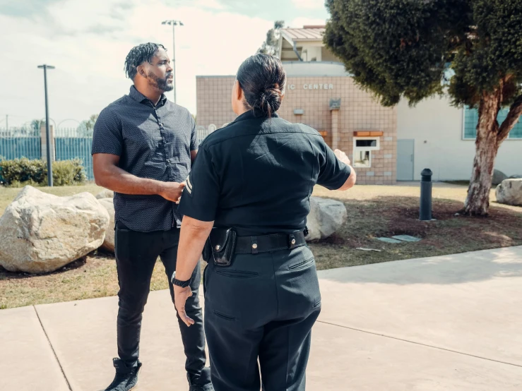 a man standing next to a woman on a skateboard, by Kristian Zahrtmann, pexels contest winner, happening, wearing a police uniform, outside in parking lot, schools, essence