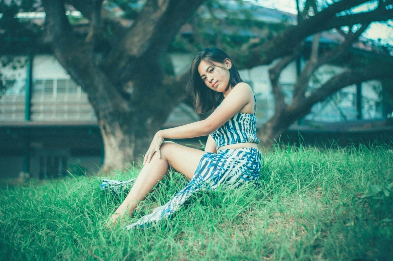 a woman sitting on top of a lush green field, patterned clothing, wearing a plastic blue dress, asian descent, portrait featured on unsplash