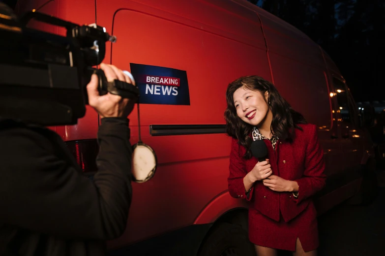a woman in a red dress standing next to a red van, pexels contest winner, private press, news broadcast, louise zhang, breaking news footage, 4k press image
