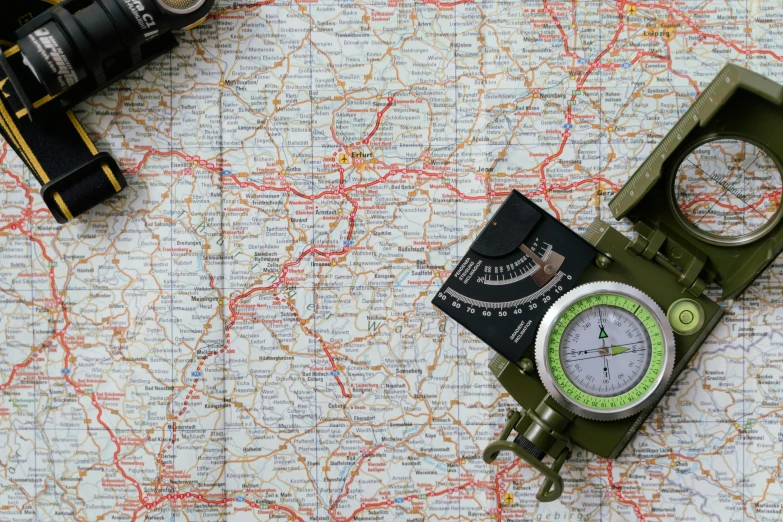 a green compass sitting on top of a map, by Adam Marczyński, pexels, military gear, highways, concert, thumbnail