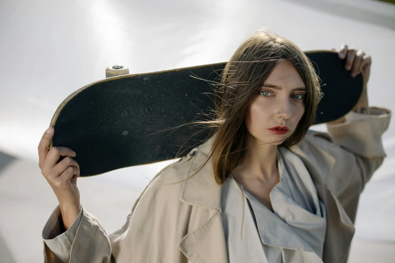 a woman holding a skateboard over her shoulder, inspired by Peter Lindbergh, unsplash contest winner, hyperrealism, wearing a long coat, neo rauch and nadav kander, angela sarafyan, high angle close up shot