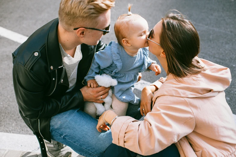 a man and woman sitting on a bench with a baby, pexels contest winner, incoherents, kissing each other, te pae, owen klatte, a group of people