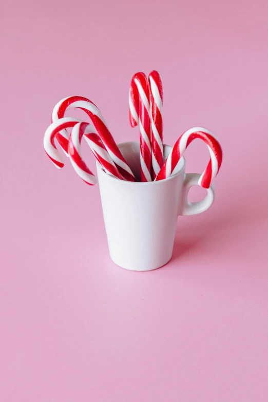 candy canes in a cup on a pink background, inspired by Peter Alexander Hay, pexels, mug shot, edible, glossy white, made of glazed