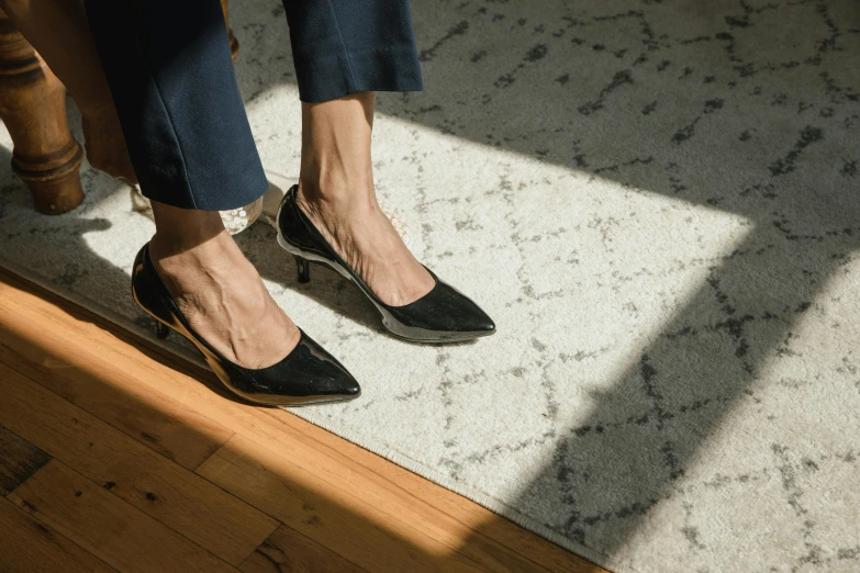 a close up of a person wearing high heels, inspired by René Burri, trending on unsplash, arabesque, sitting on the floor, wearing business casual dress, carbon black and antique gold, tilted 35° frame