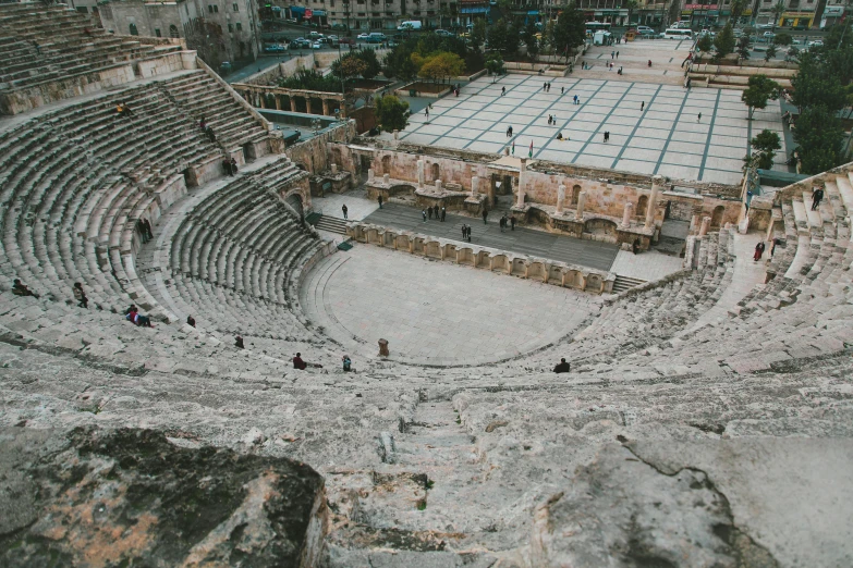 a view of a roman ampule from the top of a hill, an album cover, pexels contest winner, neoclassicism, jerusalem, photo of a huge theaterstage, ruined cities, people on the ground