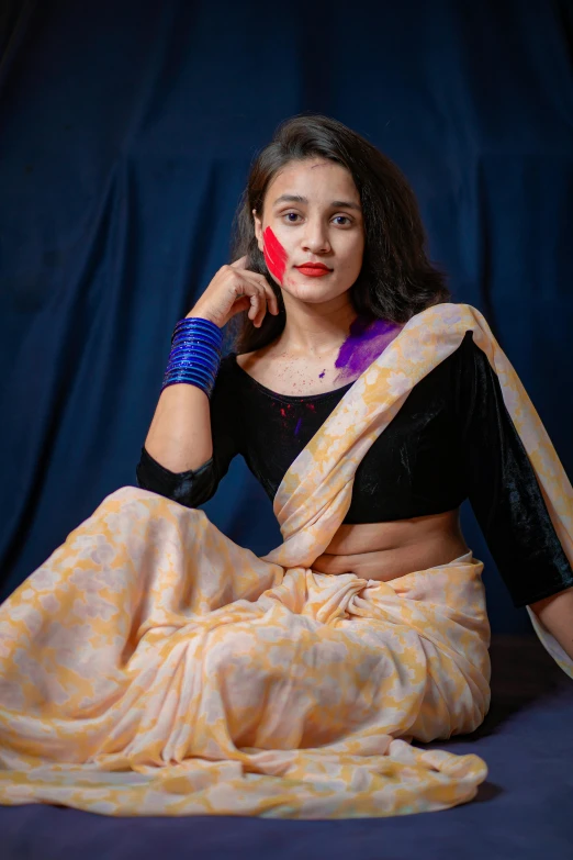 a woman sitting on the ground in a sari, non binary model, wearing a crop top, portrait image, indoor picture