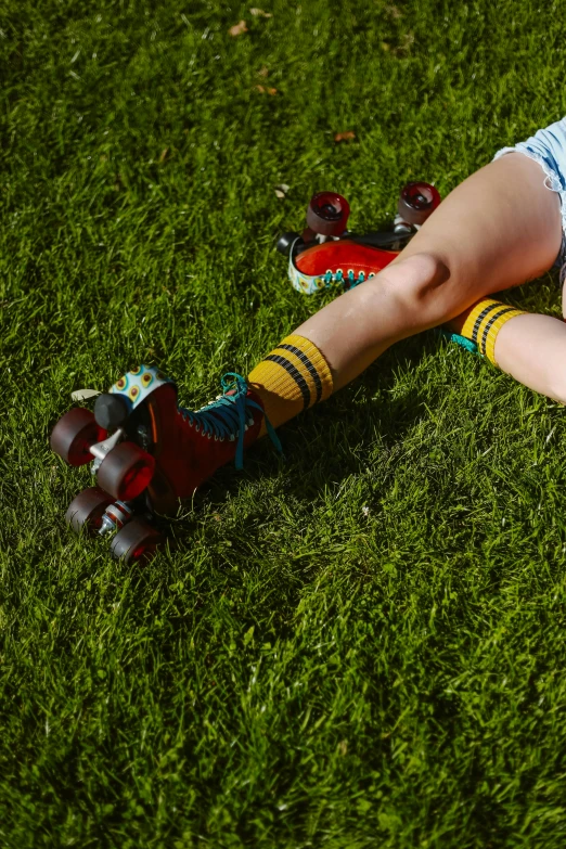 a woman laying on top of a lush green field, inspired by Elsa Bleda, pexels, graffiti, rollerskates, striped socks, yellow and red, rectangle