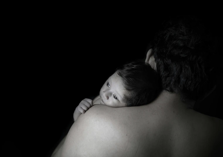 a man holding a baby in his arms, by Maciej Kuciara, art photography, portrait image, looking her shoulder, ((portrait)), backround dark