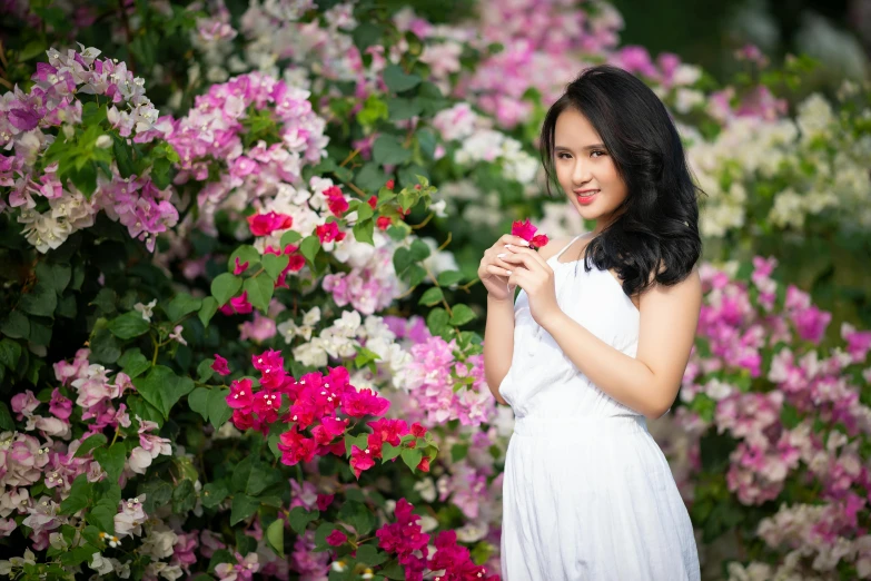 a woman standing in front of a bunch of flowers, inspired by Cui Bai, pexels contest winner, beautiful asian girl, white and pink, avatar image, outdoor photo