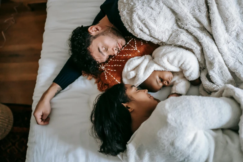 a man and a woman laying on top of a bed, by Carey Morris, pexels contest winner, with a kid, varying ethnicities, cozy, third trimester