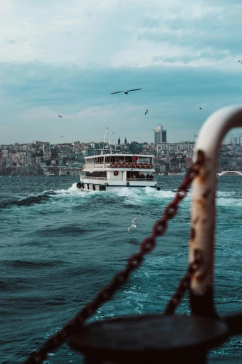 a boat on a body of water with a city in the background, by irakli nadar, pexels contest winner, turkey, turbulent sea, 🚿🗝📝, teal aesthetic