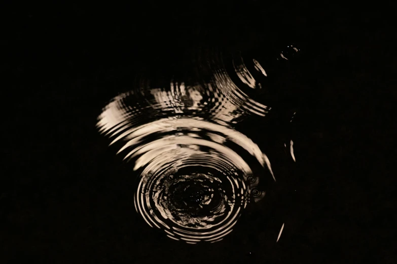 a black and white photo of a circular object, an album cover, by Raoul Ubac, water ripples, sepia photography, nighttime, whirlwind
