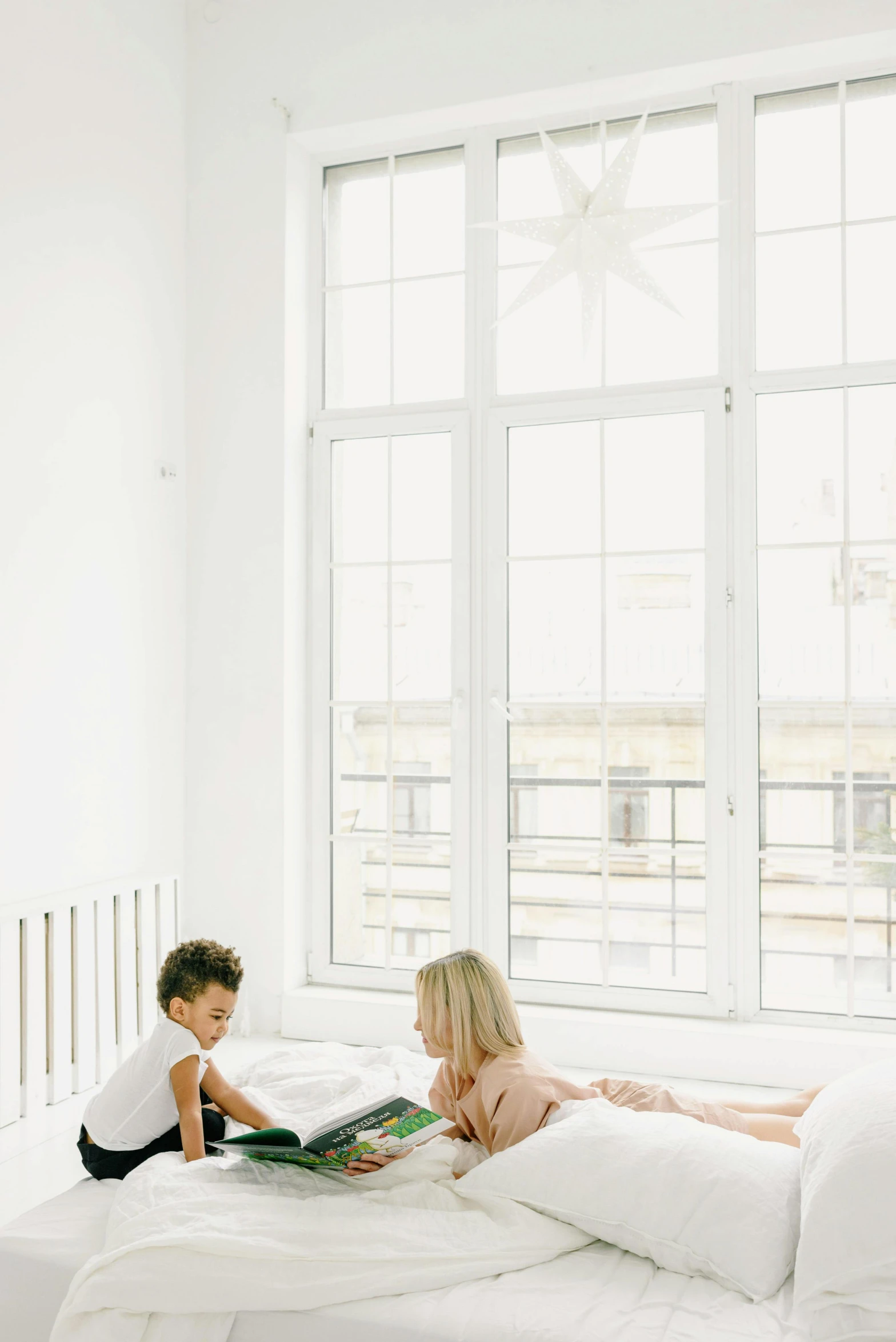 a couple of kids sitting on top of a bed, pexels contest winner, light and space, reading nook, white, promo image, tall windows