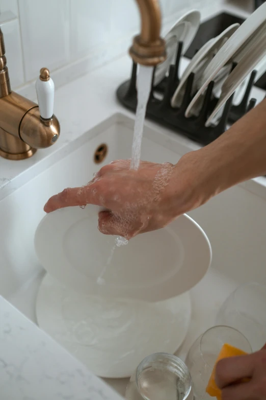 a person washing their hands in a sink, by Jessie Algie, pexels, plates, ignant, an ultra realistic, churning