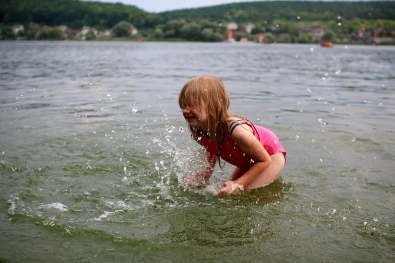 a little girl in the water playing with a frisbee, by Werner Gutzeit, pexels contest winner, lake in the background, sparky swimsuit, gooey skin, grey