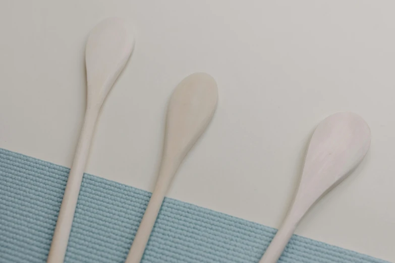 three wooden spoons sitting on top of a blue towel, inspired by Agnes Martin, unsplash, white finish, high-body detail, 1 5 9 5, mint