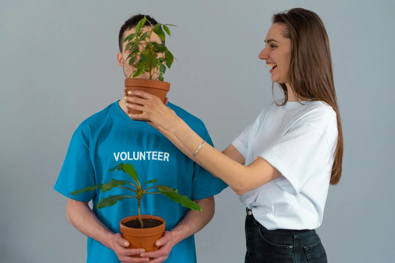 a woman standing next to a man holding a potted plant, inspired by Ernő Grünbaum, pexels contest winner, wearing a t-shirt, avatar image, profile image, a friend in need