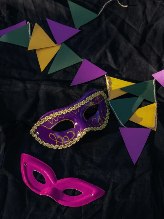 a couple of masks sitting on top of a table, by Carey Morris, trending on pexels, yellow purple green black, celebration, hood and cape, ((purple))