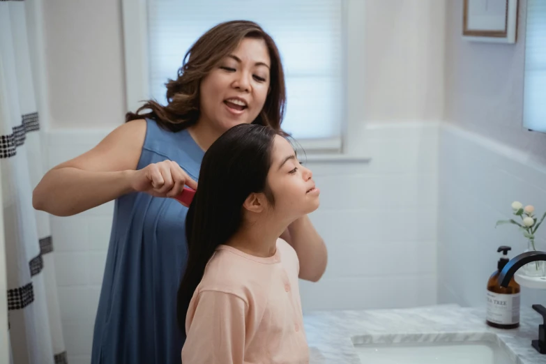 a woman brushing a young girl's hair in a bathroom, by Olivia Peguero, pexels contest winner, renaissance, an asian woman, profile image, hairspray, pictured from the shoulders up