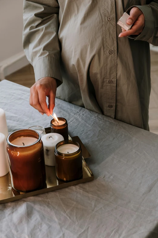 a man lighting candles on a tray on a table, trending on unsplash, sustainable materials, brown, waking up, soft volume absorbation