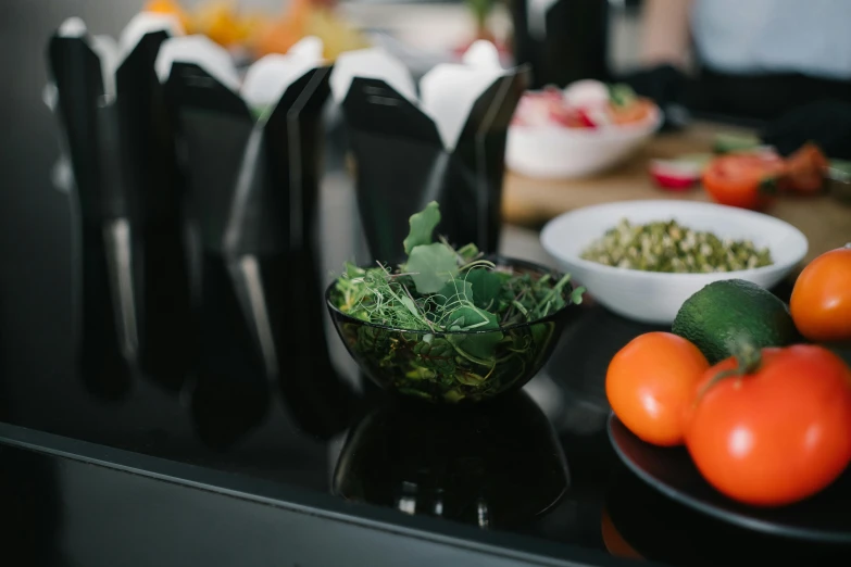 a black table topped with bowls of fruit and vegetables, unsplash, private press, standing in a restaurant, profile image, vegetable foliage, medium closeup