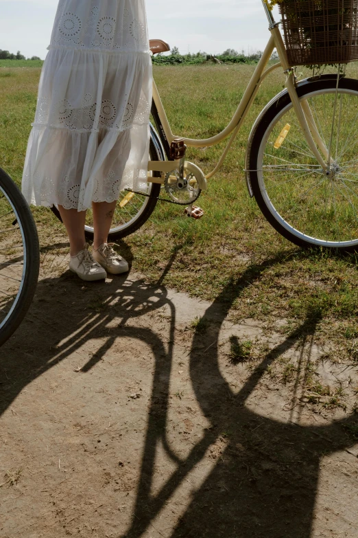 a woman standing next to a bike with a basket on the back, pexels contest winner, long shadows, close-up on legs, wedding, cottagecore hippie