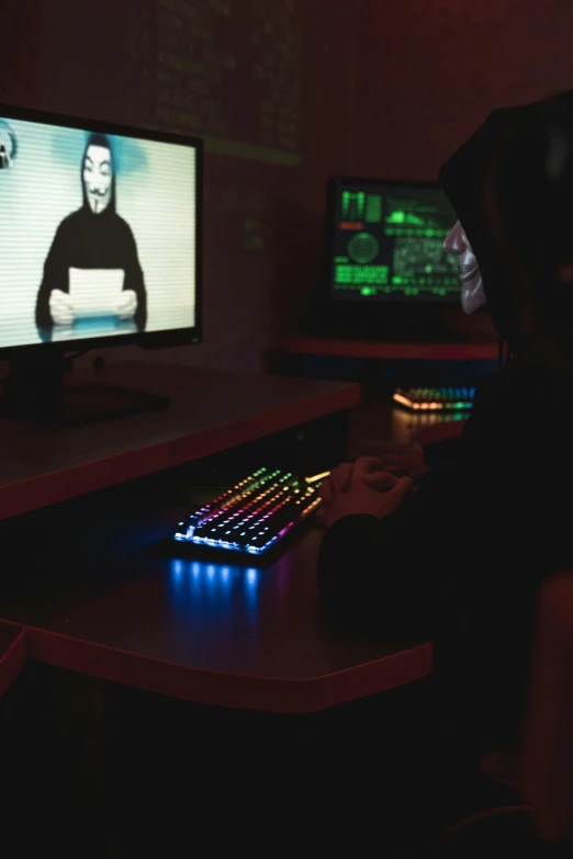 a person sitting at a desk in front of a computer, a hologram, pexels, anonymous mask, gaming room, 2 5 6 x 2 5 6 pixels, still from film