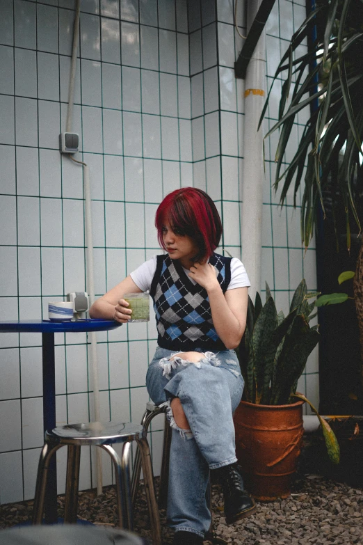 a woman with red hair sitting at a table, an album cover, by Yuki Ogura, trending on pexels, outfit : jeans and white vest, drinking boba tea, checkered spiked hair, covered in plants