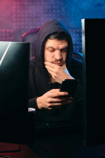 a man in a hoodie looking at a cell phone, skin on the gaming pc, looking distracted and awkward, 🔥 😎 🕹️ 👀 :2, nights