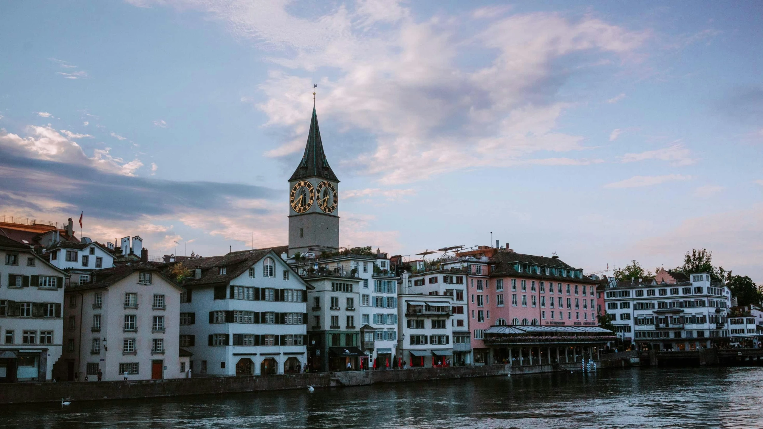 a group of buildings next to a body of water, by Julia Pishtar, pexels contest winner, art nouveau, grossmünster, clock tower, tie-dye, youtube thumbnail