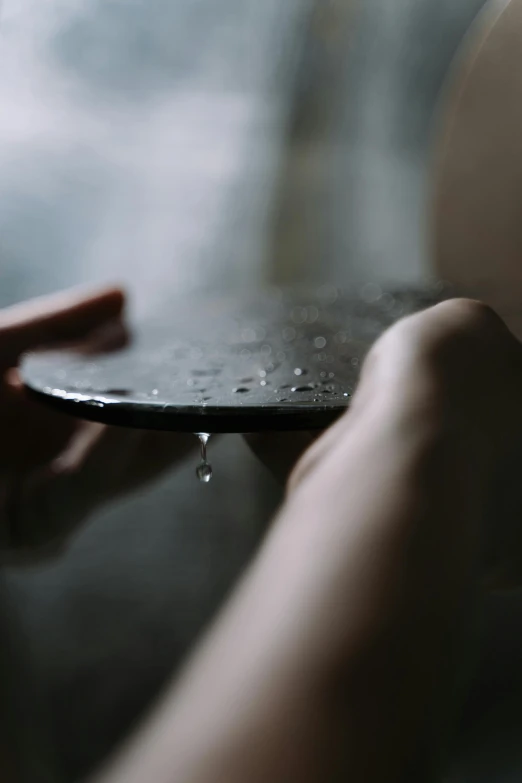 a person holding a plate with water on it, inspired by Elsa Bleda, trending on unsplash, made of smooth black goo, big drops of sweat, slate, morning time