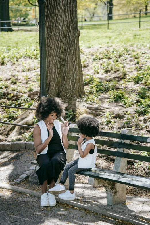 two children sitting on a bench in a park, by Nina Hamnett, pexels contest winner, photo of a black woman, snacks, ny, big hair