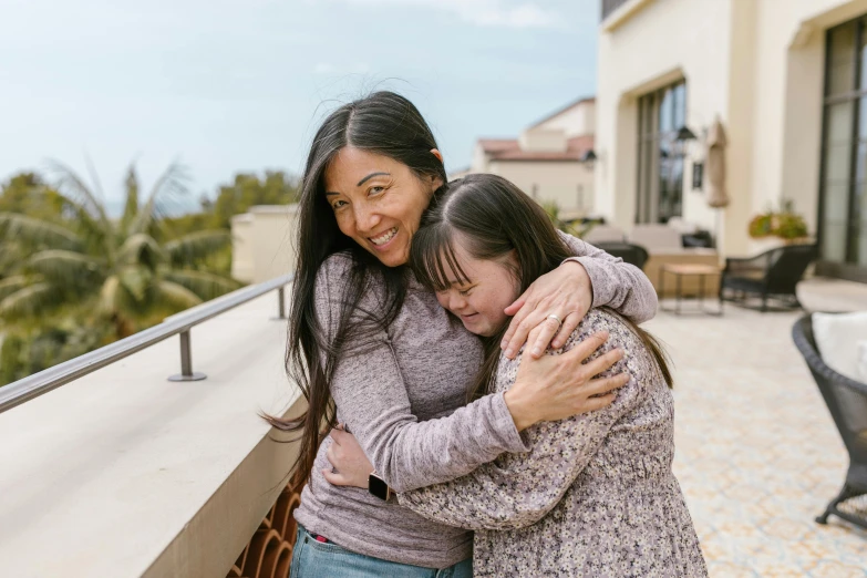 two women hugging each other on a balcony, pexels contest winner, happening, asian descent, oceanside, holding an epée, charli bowater and artgeem