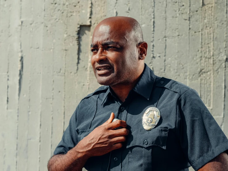a man in a police uniform standing in front of a wall, pexels contest winner, dave chappelle, devastated, chest up bust shot, los angeles ca
