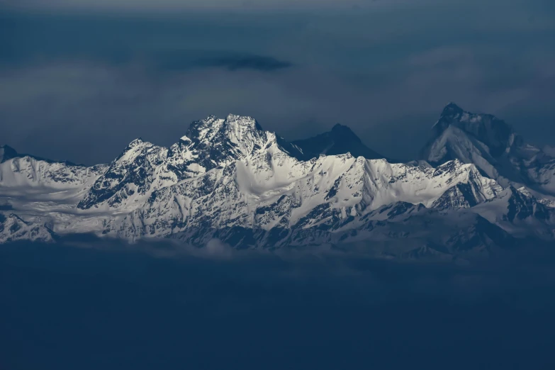 a large mountain covered in snow under a cloudy sky, an album cover, pexels contest winner, hurufiyya, himalayas, dimly lit, telephoto, airborne view