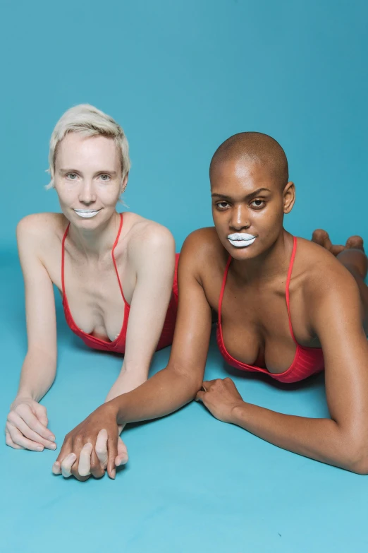 a couple of women laying on top of each other, an album cover, inspired by Vanessa Beecroft, unsplash, feminist art, white prosthetic eyes, bald patch, is wearing a swimsuit, jaw and tongue