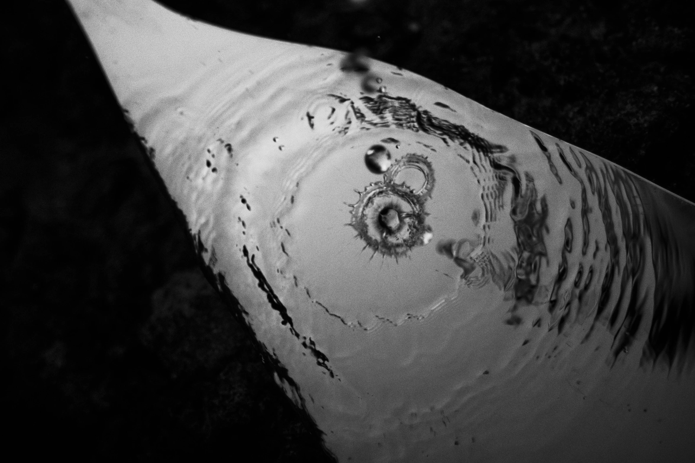 a close up of a pipe with water coming out of it, a microscopic photo, inspired by Edward Weston, flickr, land art, with a squid tattoo, fotografia blanco y negro, droplets flow down the bottle, haida gwaii