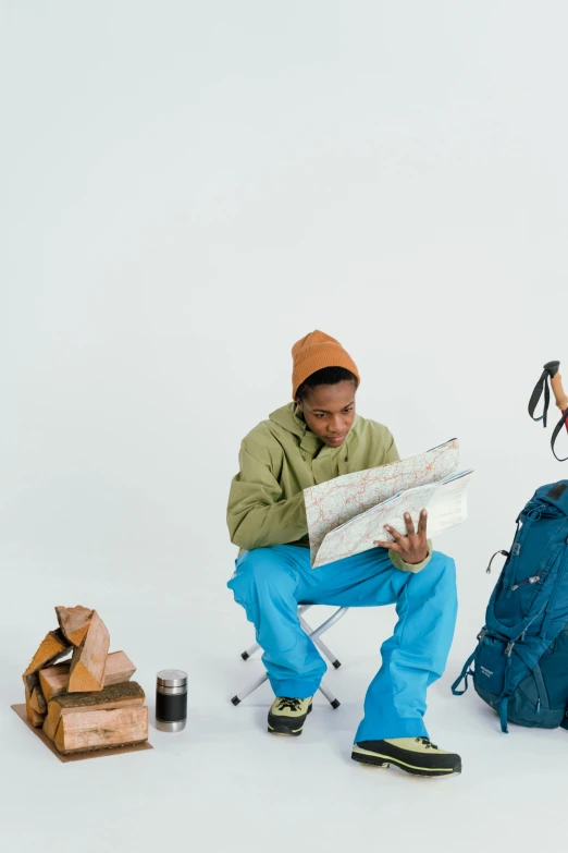 a man sitting on top of a chair next to a backpack, by Alice Mason, trending on unsplash, visual art, map cartography, wearing teal beanie, jemal shabazz, wizard reading a directory