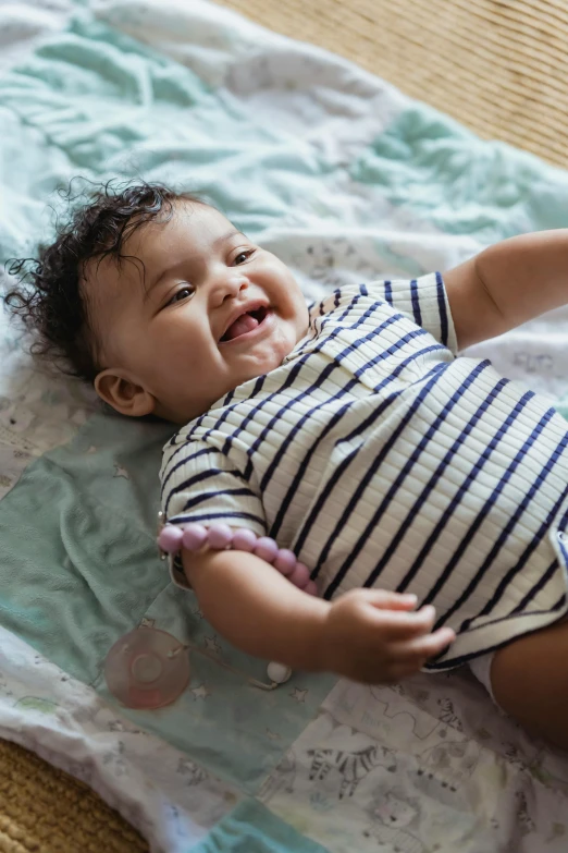 a baby laying on top of a blanket on a floor, a picture, shutterstock contest winner, happening, smiling playfully, bumpy, top down shot, uk