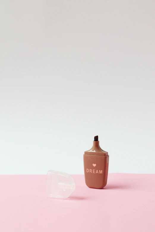 a bottle of cream sitting on top of a pink surface, by Bryan Organ, unsplash, conceptual art, hand carved brown resin, lipstick, vinyl designer toy, copper cup