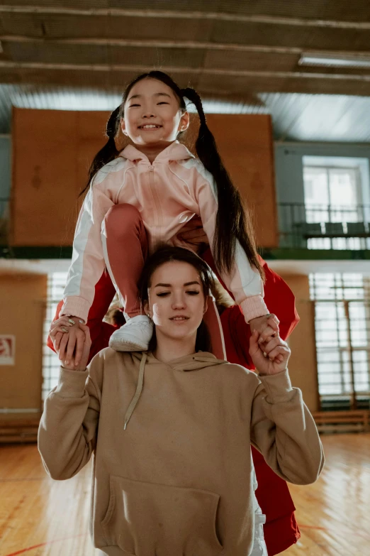 a woman holding a little girl on her shoulders, pexels contest winner, in the high school gym, maxim sukharev, chinese heritage, aurora aksnes and zendaya