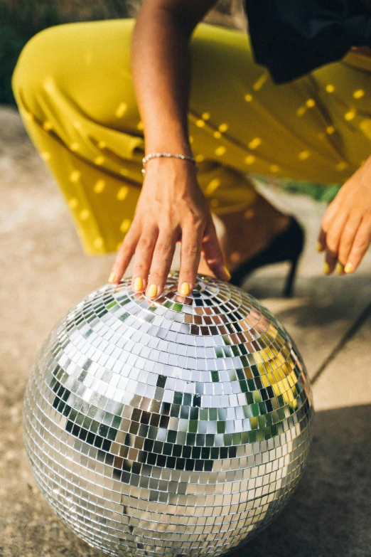 a close up of a person holding a disco ball, lady using yellow dress, satin silver, discogs, beautiful surroundings