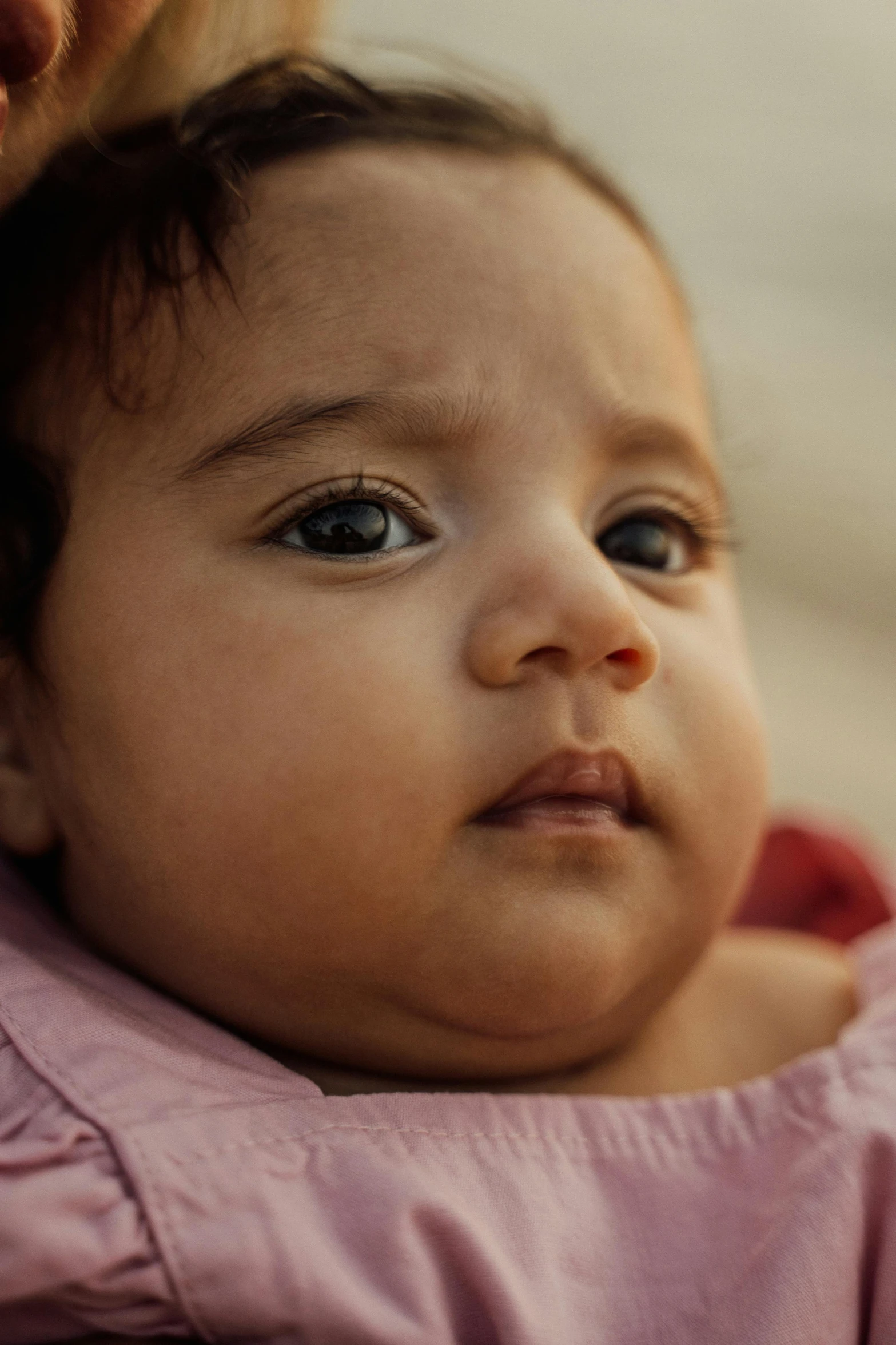 a close up of a person holding a baby, focused face, light-brown skin, middle eastern skin, red cheeks