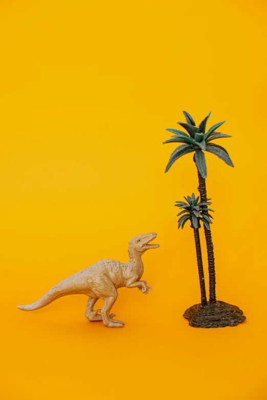 a toy dinosaur standing next to a palm tree, a statue, inspired by Adam Rex, trending on unsplash, yellow backdrop, 3d asset, museum quality photo, multiple stories