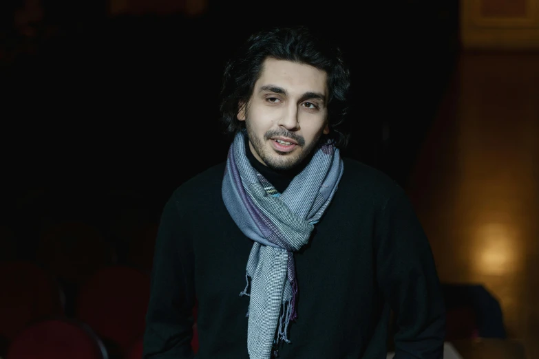 a man standing in a dark room wearing a scarf, sayem reza, a young man, promo image, multiple stories