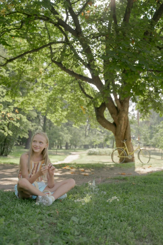 a woman sitting on the grass in front of a tree, snacks, panoramic centered view of girl, cinematic shot ar 9:16 -n 6 -g, anastasia ovchinnikova